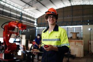 ingeniero revisando el panel de control y enseñando el nuevo brazo robótico automático y la máquina de control operativo en fábrica. foto