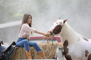 mujer joven con su caballo en la luz del atardecer. fotografía al aire libre con una modelo de moda. estado de ánimo de estilo de vida foto