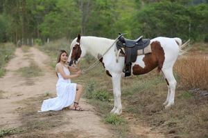 mujer joven con su caballo en la luz del atardecer. fotografía al aire libre con una modelo de moda. estado de ánimo de estilo de vida foto