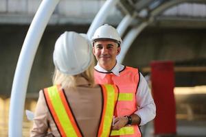 el ingeniero y la mujer de negocios revisando el portapapeles en el edificio del sitio de construcción. el concepto de ingeniería, construcción, vida urbana y futuro. foto