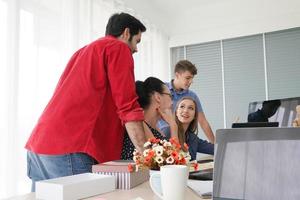 grupo diverso de jóvenes empresarios discutiendo un proyecto de trabajo mientras se sientan juntos en una mesa en una oficina moderna. concepto de coworking foto