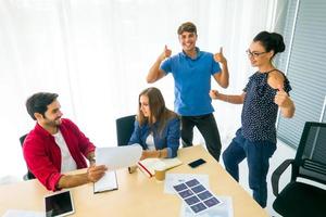 Diverse group of young business people discussing a work project while sitting together at a table in a modern office. coworking concept photo
