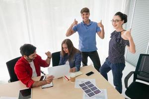 grupo diverso de jóvenes empresarios discutiendo un proyecto de trabajo mientras se sientan juntos en una mesa en una oficina moderna. concepto de coworking foto