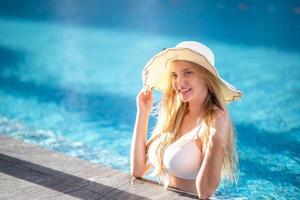woman in white bikini tanning by the pool photo