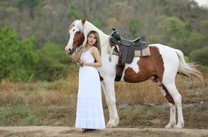 mujer joven con su caballo en la luz del atardecer. fotografía al aire libre con una modelo de moda. estado de ánimo de estilo de vida foto