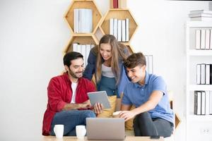 grupo diverso de jóvenes empresarios discutiendo un proyecto de trabajo mientras se sientan juntos en una mesa en una oficina moderna. concepto de coworking foto