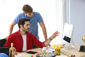 grupo diverso de jóvenes empresarios discutiendo un proyecto de trabajo mientras se sientan juntos en una mesa en una oficina moderna. concepto de coworking foto