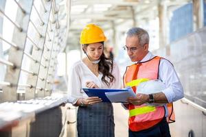 el ingeniero y la mujer de negocios revisando el portapapeles en el edificio del sitio de construcción. el concepto de ingeniería, construcción, vida urbana y futuro. foto