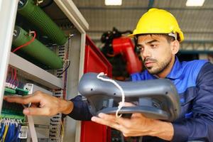 Industrial engineer or worker wearing a helmet while standing in a heavy industrial factory. The Maintenance looking of working at industrial machinery and check security system setup in factory. photo