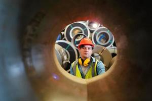 el capataz de los trabajadores de la industria o el trabajo de los trabajadores en el sitio de la fábrica revisan la máquina o los productos en el sitio. ingeniero o técnico revisando material o máquina en planta. industrial y fábrica. foto