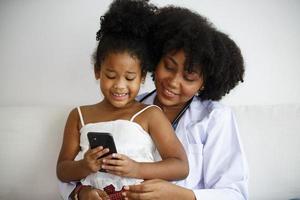 Mixed race mother and her daughter looking on mobile phone with fun. photo