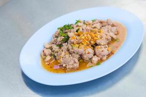 la ensalada de cerdo picada picante es una comida tradicional del noreste de tailandia. contiene cerdo picado, arroz asado, chile asado y hierbas tailandesas mezcladas. se puso en un plato blanco. foto