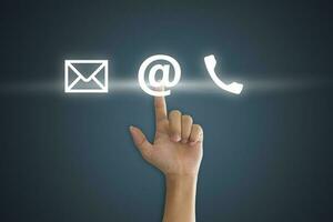 Hand pressing telephone, email button icon over blue background. Customer support concept photo