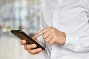 Close-up of male hand using smartphone. Businessman  touch mobile phone with bokeh background. Selective focus on hand. photo