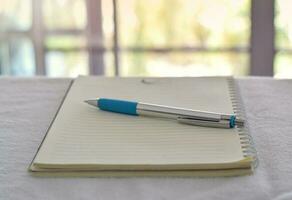 Close up of pen in notebook on office desk with blurry background. photo