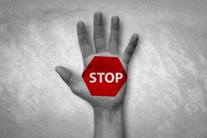 Hand raised with stop sign painted. Emotional black and white photo with red symbol.