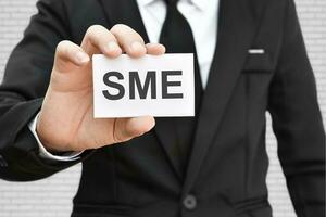 mano de hombre sosteniendo una tarjeta de papel con la palabra sme. concepto de negocio de pequeñas y medianas empresas. foto