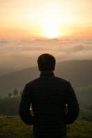 man watching sunrise at hilltop photo