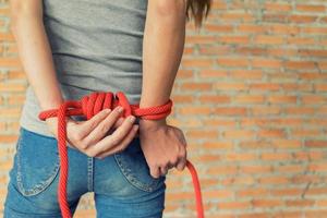 Tied rope hands of abused woman photo