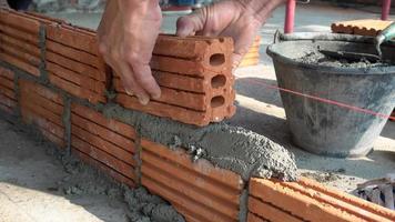 Bricklayer worker installing brick masonry on exterior wall photo