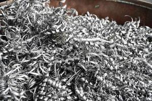 Steel scrap materials recycling. Aluminum chip waste after machining metal parts on a cnc lathe. Closeup twisted spiral steel shavings. Small roughness sharpness, photo
