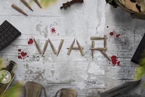 War composition on rough surface writen with bullets and surrounded with blood drops. Military equipment beside. Top view, flat lay photo