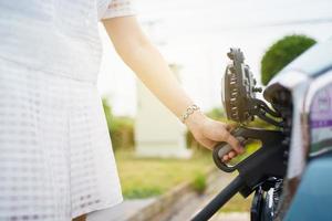 mujer asiática sosteniendo un conector de carga ac tipo 2 ev en la estación de carga ev, mujer preparando un ev - conector de carga de vehículos eléctricos para recargar un vehículo. foto