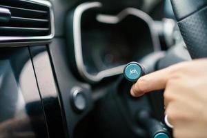 Unrecognizable man driver activating the adaptive cruise control or steering assistant on the control stick behind steering wheel in electric vehicle - EV. Driving Assist system in modern car. photo