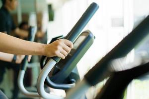 joven asiático activo haciendo un ejercicio cardiovascular en la máquina elíptica en el gimnasio. quema de grasa y musculación corporal. concepto de entrenamiento de culturismo. foto