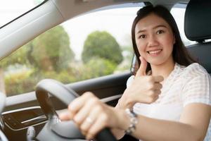 Unrecognizable female driver using left hand grabs on the steering wheel while driving on the road, woman driving a modern electric car EV in beautiful sunlight on the road. Safety driving concept. photo