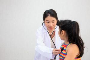 Professional specialist doctor examining about breathing in Asian little girl in kids hospital. Doctor kindly checking and listening heartbeat in little girl. photo