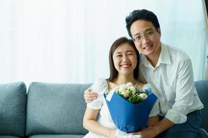 Husband surprising his wife in the anniversary day with a beautiful bouquet of flower. photo