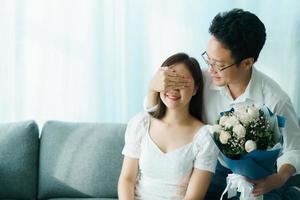 esposo sorprendiendo a su esposa en el día del aniversario con un hermoso ramo de flores. foto