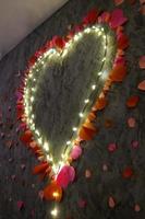 A flaming heart of light bulbs and rose petals made of wire. Romantic setting photo