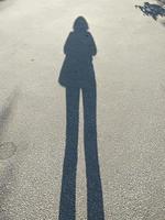 sombra de una chica alta en una carretera asfaltada. foto
