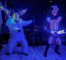 Life-size puppets in the form of robots on a stage. Funny amateur dance photo