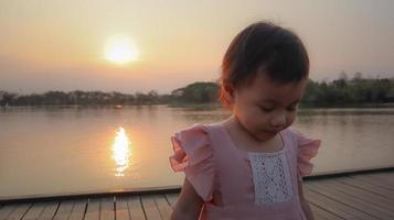 Blurred photo. Charming 3 years old Asian little girl with pink dress looking down to the floor. photo