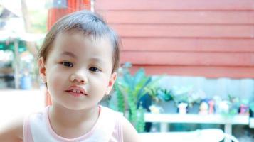 Headshot of charming 3 years old cute baby Asian girl, little toddler child with adorable brown less hair. photo