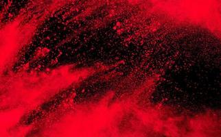 Red powder explosion on black background. Freeze motion of red dust particle splash. photo