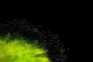 Abstract green dust splattered on black background. Freeze motion of green powder splash. photo