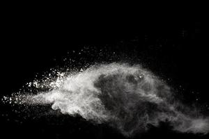 White powder explosion isolated on black background. White dust particles splash.Color Holi Festival. photo