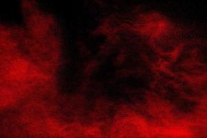 Red powder explosion cloud on black background. Freeze motion of red color dust  particles splashing. photo