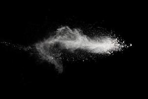 White powder explosion isolated on black background.White dust particles splash. photo