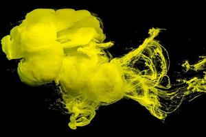 Yellow ink drop swirling on background. Cloud of acrylic ink.Color drops in water. photo