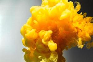 Color drops in water.Yellow ink drop swirling on background. Cloud of acrylic ink. photo