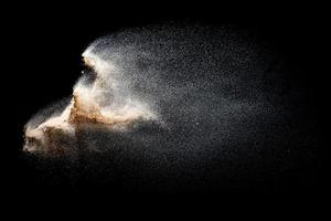 Sand flying explosion isolated on black background. Freeze motion of sandy dust splash. photo