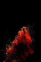 Red orange color powder explosion cloud isolated on black background. photo