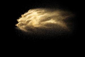 Abstract sand cloud.Golden colored sand splash agianst dark background.Yellow sand fly wave in the air. Sand explode on black background ,throwing freeze stop motion concept. photo