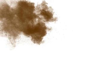 Freeze motion of brown powder exploding. Abstract design of color powder cloud against white background. photo