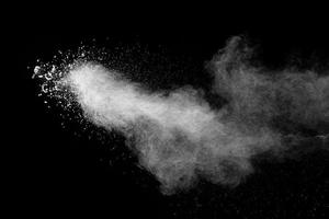 White dust particles splashing. Freez motion of talcum powder burst in dark background. photo